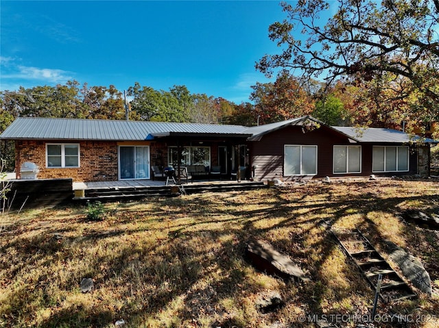 rear view of property featuring a yard and metal roof