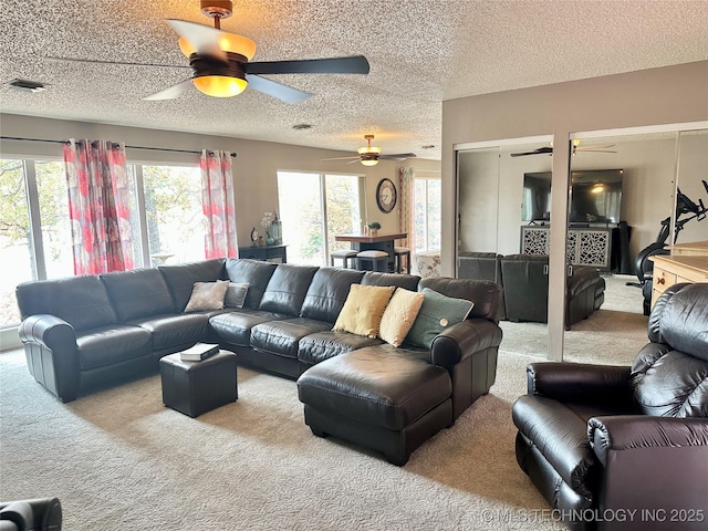 carpeted living room featuring visible vents, a textured ceiling, and ceiling fan