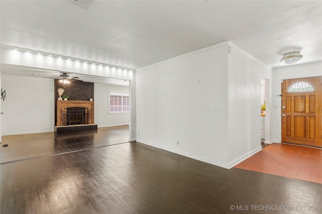 entrance foyer featuring visible vents, a brick fireplace, wood finished floors, baseboards, and ceiling fan