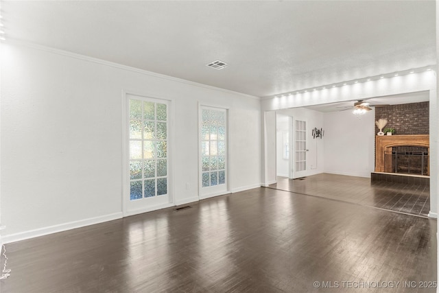 unfurnished living room featuring visible vents, baseboards, a brick fireplace, and wood finished floors
