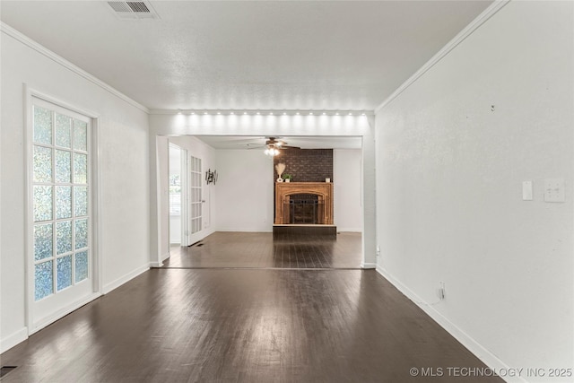 unfurnished living room featuring a healthy amount of sunlight, crown molding, wood finished floors, and visible vents