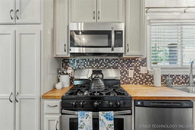 kitchen featuring decorative backsplash, a sink, butcher block counters, stainless steel appliances, and white cabinetry