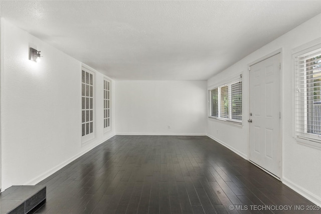 empty room with baseboards, a textured ceiling, and dark wood-type flooring