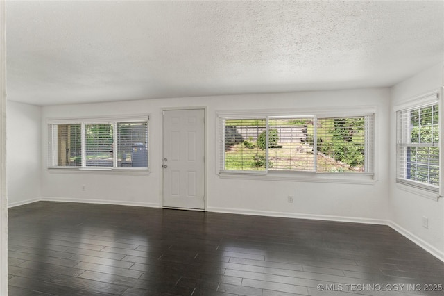 unfurnished living room with baseboards, dark wood-style floors, and a textured ceiling