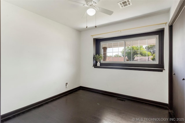 empty room featuring a ceiling fan, baseboards, visible vents, and wood finished floors