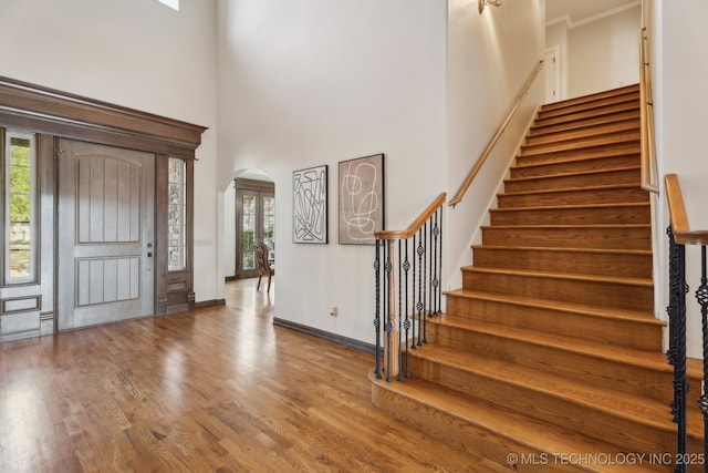 foyer entrance with stairway, arched walkways, a high ceiling, and a wealth of natural light