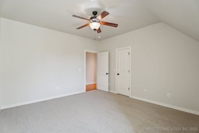 interior space featuring baseboards, ceiling fan, lofted ceiling, and light colored carpet