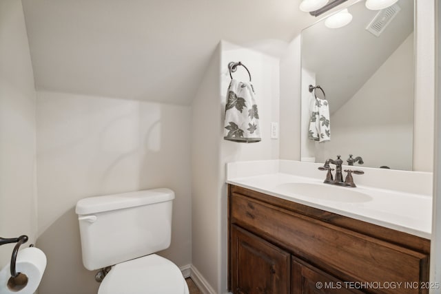 half bath featuring vanity, lofted ceiling, toilet, and visible vents