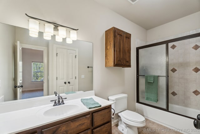 bathroom featuring toilet, bath / shower combo with glass door, and vanity