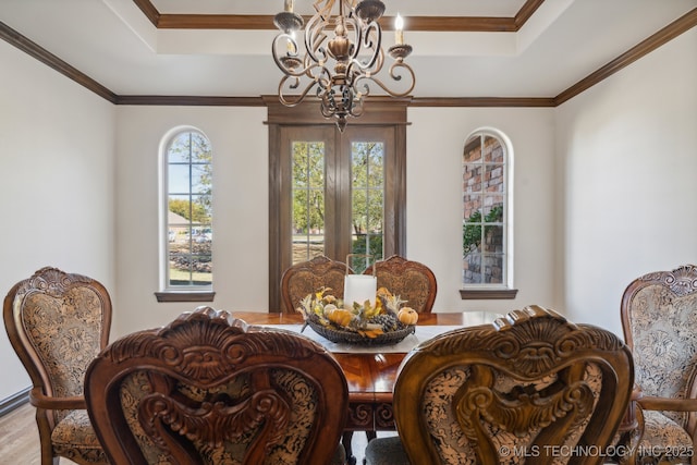 dining room with an inviting chandelier, a raised ceiling, and wood finished floors