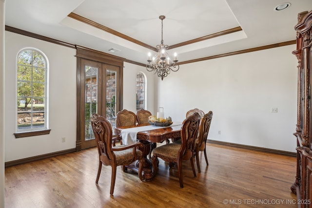 dining room featuring baseboards, a tray ceiling, a chandelier, and wood finished floors
