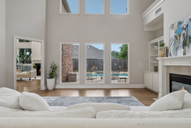 living room with visible vents, a high ceiling, a fireplace, and wood finished floors
