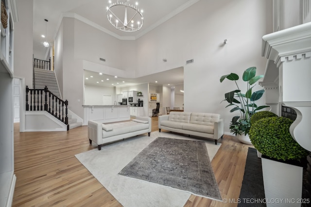 living area featuring stairs, a high ceiling, an inviting chandelier, and light wood-type flooring