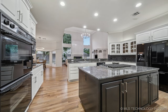 kitchen with visible vents, crown molding, a sink, black appliances, and a peninsula