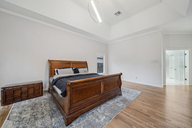 bedroom with baseboards, visible vents, ornamental molding, and light wood-style floors
