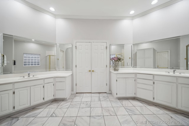 bathroom with a sink, ornamental molding, and two vanities