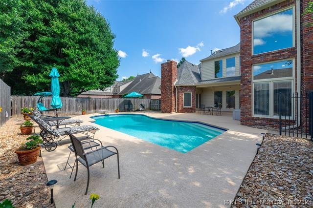 view of swimming pool with a fenced backyard, a fenced in pool, a diving board, and a patio area