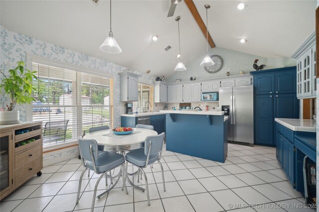 19978 E Murrell Rd, Tahlequah, OK 74464 - kitchen with wallpapered walls, stainless steel appliances, blue cabinets, and vaulted ceiling with beams