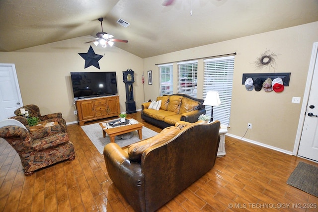 living room featuring ceiling fan, visible vents, vaulted ceiling, baseboards, and light wood-style floors