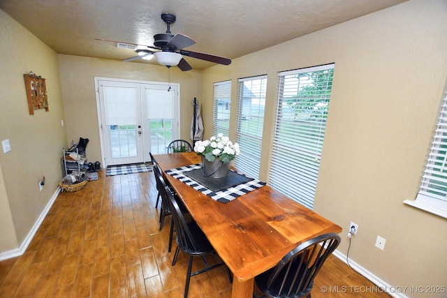 dining space with a ceiling fan, baseboards, visible vents, and wood finished floors