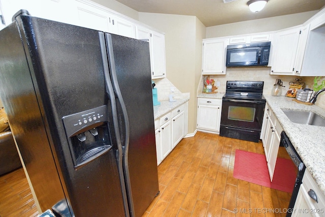 kitchen with decorative backsplash, a sink, white cabinets, black appliances, and light wood finished floors