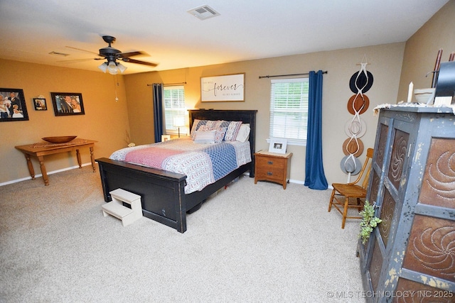 carpeted bedroom featuring visible vents, a ceiling fan, baseboards, and a fireplace