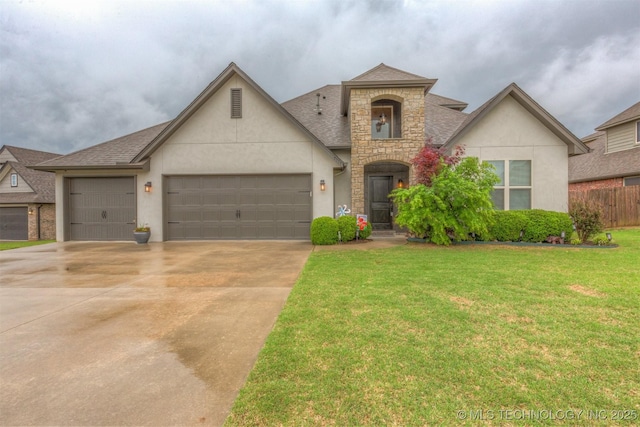 view of front of house featuring driveway, a front yard, an attached garage, stone siding, and stucco siding