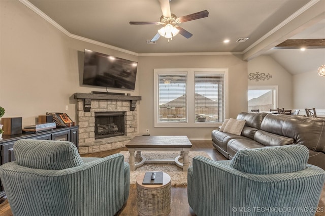 living area featuring a stone fireplace, ceiling fan, wood finished floors, and vaulted ceiling with beams