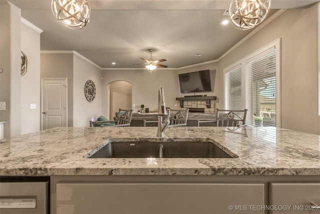 kitchen with a sink, arched walkways, crown molding, and open floor plan