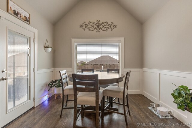 dining area featuring dark wood finished floors, wainscoting, lofted ceiling, and a decorative wall