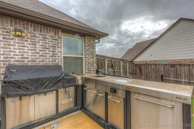 view of patio / terrace featuring a sink, fence, area for grilling, and a grill