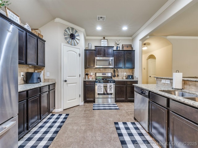 kitchen featuring visible vents, dark brown cabinets, tasteful backsplash, arched walkways, and appliances with stainless steel finishes