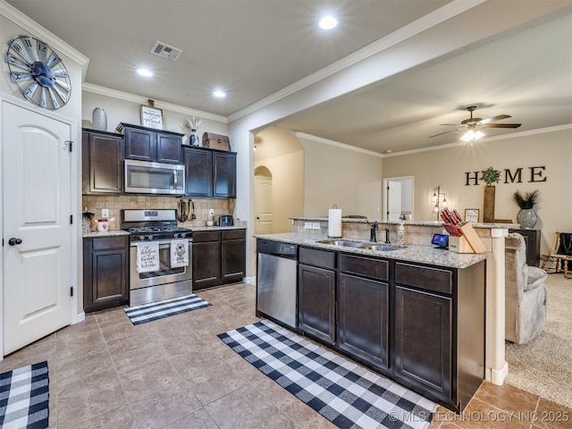 kitchen featuring a sink, arched walkways, stainless steel appliances, tasteful backsplash, and visible vents
