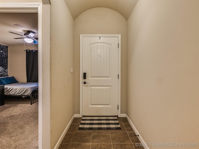 doorway to outside featuring dark tile patterned floors, baseboards, and a ceiling fan