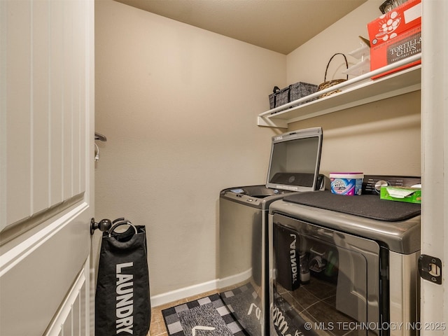 clothes washing area with baseboards, laundry area, and washer and clothes dryer