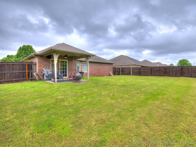 rear view of house featuring a ceiling fan, brick siding, a fenced backyard, a yard, and a patio
