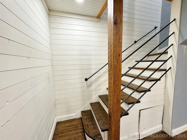 staircase featuring wood walls and wood finished floors