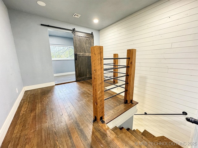 stairs featuring baseboards, visible vents, a barn door, and hardwood / wood-style floors