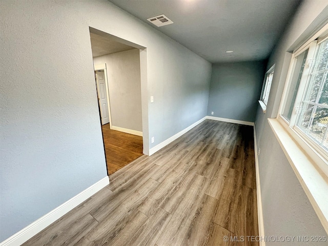 unfurnished room featuring visible vents, baseboards, and wood finished floors