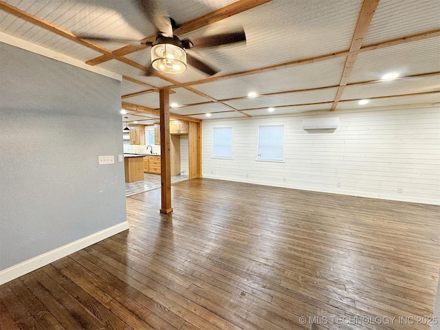 interior space with wooden walls, a ceiling fan, baseboards, and dark wood-style floors
