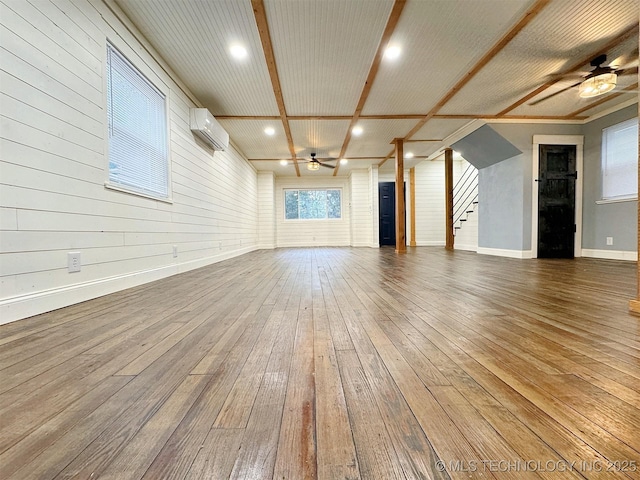 unfurnished living room featuring ceiling fan, an AC wall unit, hardwood / wood-style flooring, recessed lighting, and stairway