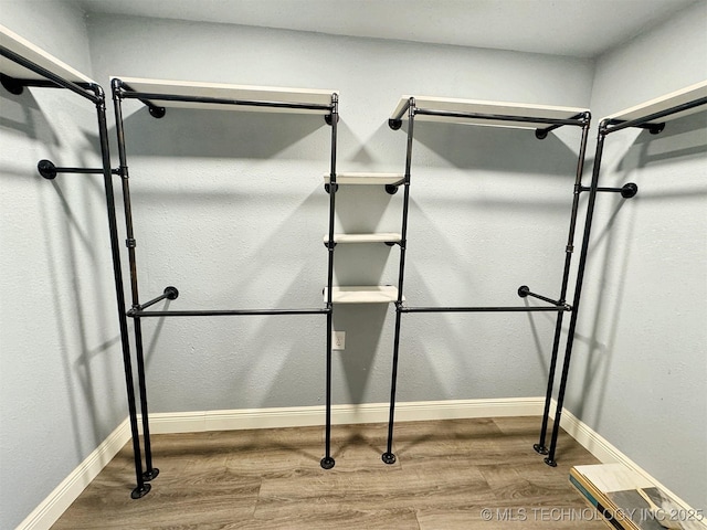walk in closet with wood finished floors