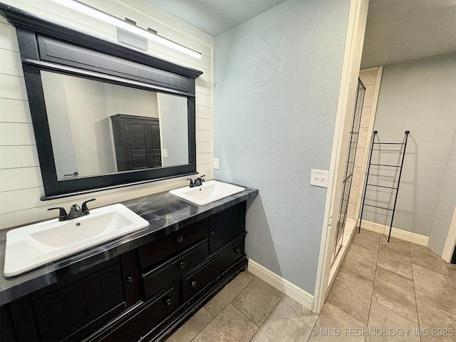 bathroom with a sink, tile patterned flooring, and a textured wall