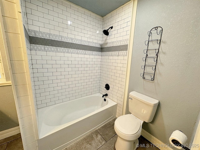 full bath with baseboards, tile patterned floors, washtub / shower combination, and toilet
