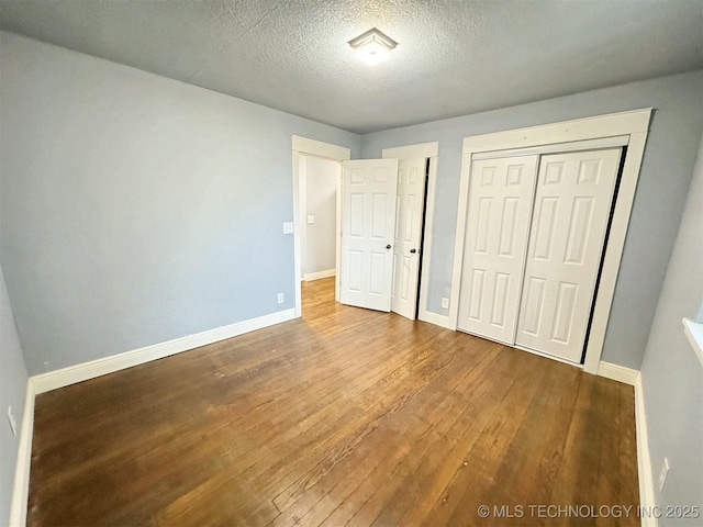 unfurnished bedroom with baseboards, a textured ceiling, and wood finished floors