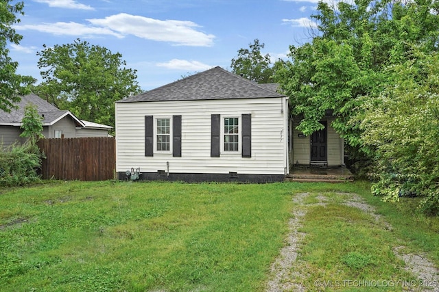 exterior space with a lawn, crawl space, fence, and roof with shingles