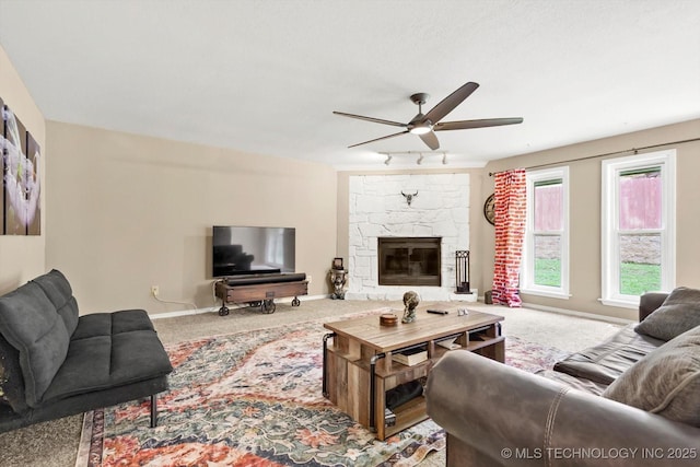 living room featuring carpet flooring, a ceiling fan, baseboards, and a fireplace