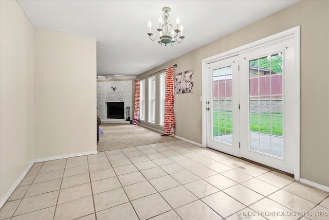 unfurnished living room with a notable chandelier, plenty of natural light, visible vents, and a fireplace
