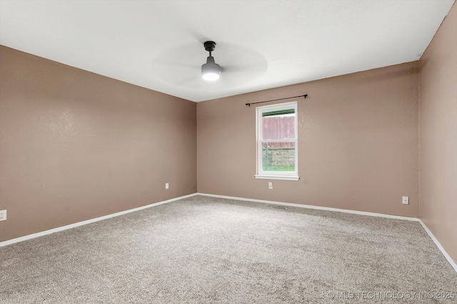 carpeted spare room featuring a ceiling fan and baseboards