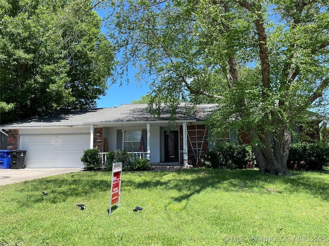 single story home with covered porch, an attached garage, driveway, and a front yard